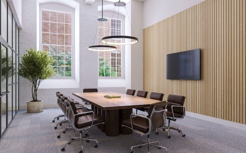 Large room with conference table and chairs with a tv and plants with large windows