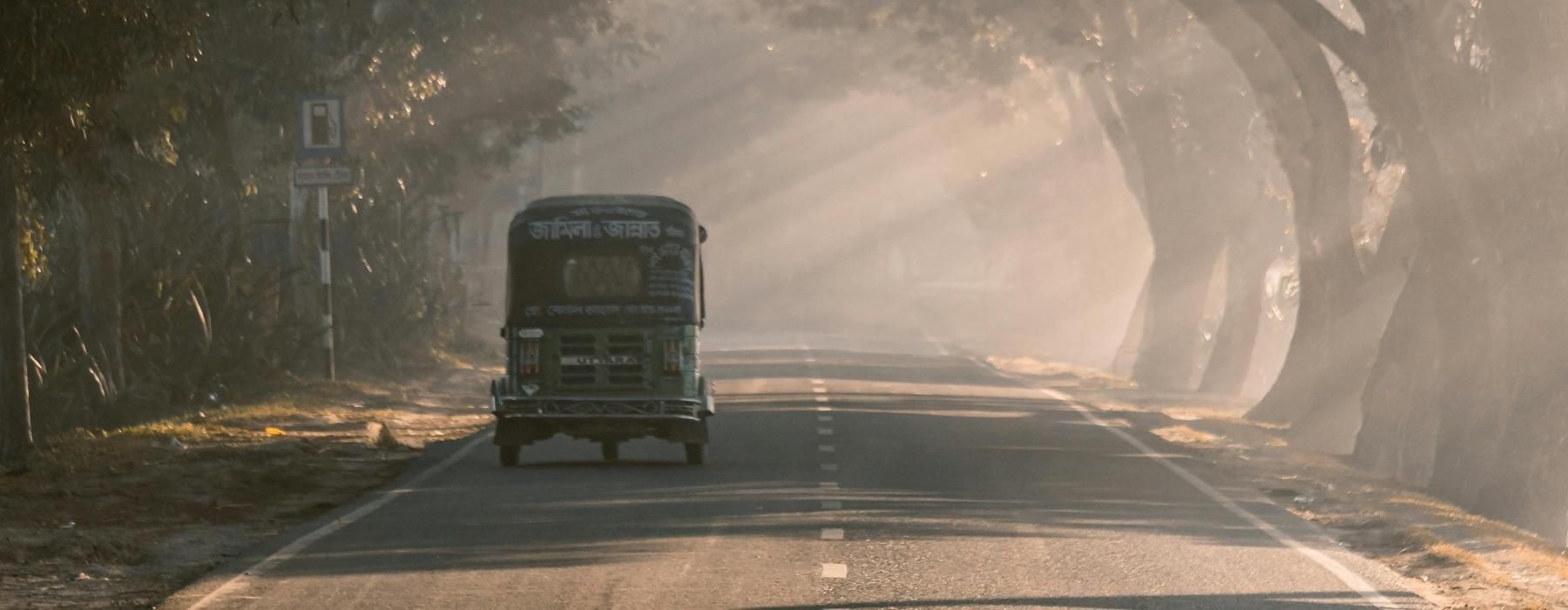 a bus driving down a road with trees on either side of it