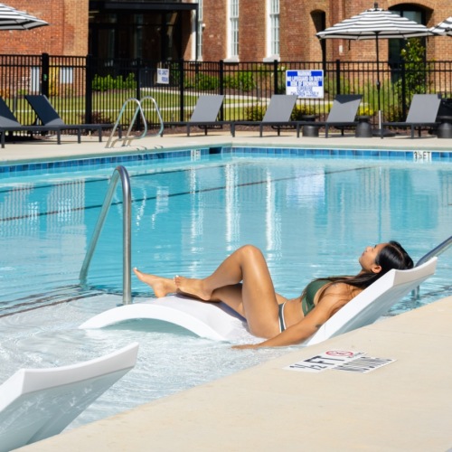 Shimmering resort-style pool woman relaxing on a chair in the pool