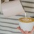 Person pouring creamer into coffee at coffee shop 